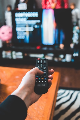 A person holding a remote control in front of a tv.
