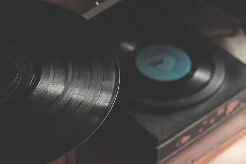 A black vinyl record is placed on a wooden table, showcasing the importance of Physical Music Distribution.