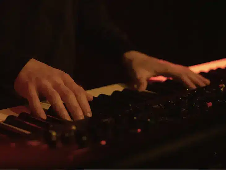 A person playing an electronic keyboard in a dimly lit room while reading a letter from Symphonic's CEO.