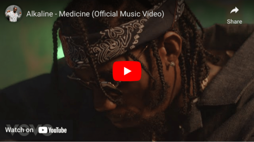 Man with braided hair and sunglasses wearing a headband, looking downward, in a scene from the "medicine" video distributed by Alkaline.