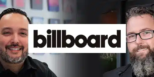 Two men smiling, each on one side of the image, with the Billboard logo in bold text centered between them, giving the scene a press-ready feel.