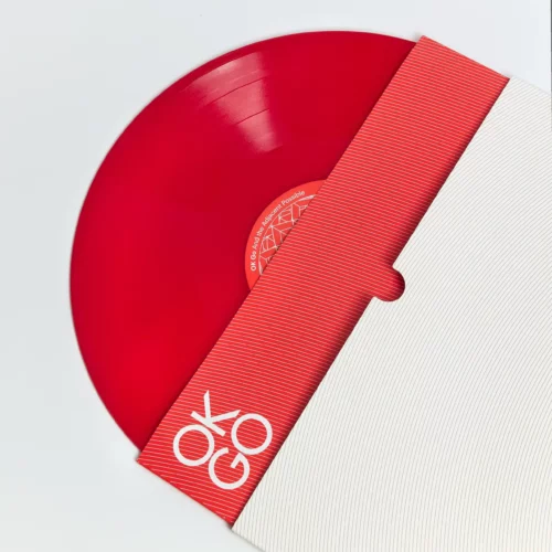 A red vinyl record, symbolizing physical music distribution, is partially pulled from a white and red striped sleeve with "OKOGO" printed boldly in the corner.