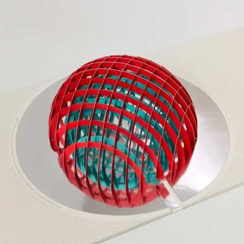 A pop-up book features a red and teal spherical lattice structure rising from a silver reflective circle on a white background, reminiscent of the tactile appeal found in physical music distribution.