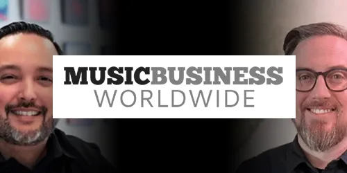 Two smiling men appear on either side of a "Music Business Worldwide" logo, centered over a black background, creating an image reminiscent of a press announcement.